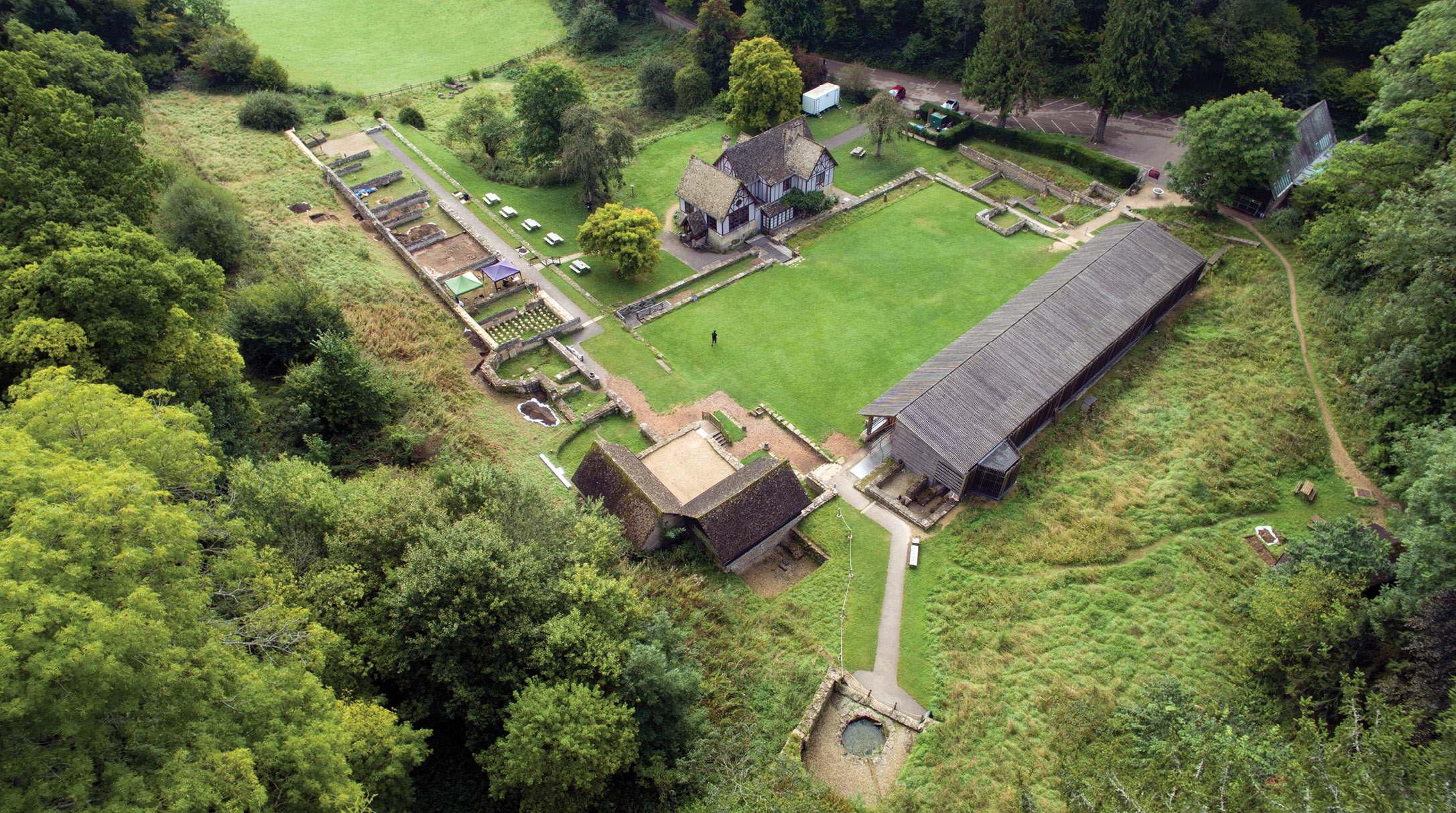 below This drone photograph (looking south-east) shows the extent of the villa complex at Chedworth: bottom centre we see the Nymphaeum, built at a natural spring, with bathhouses on either side of it. The North Range of villa buildings lie to the left, and the West Range to the right.