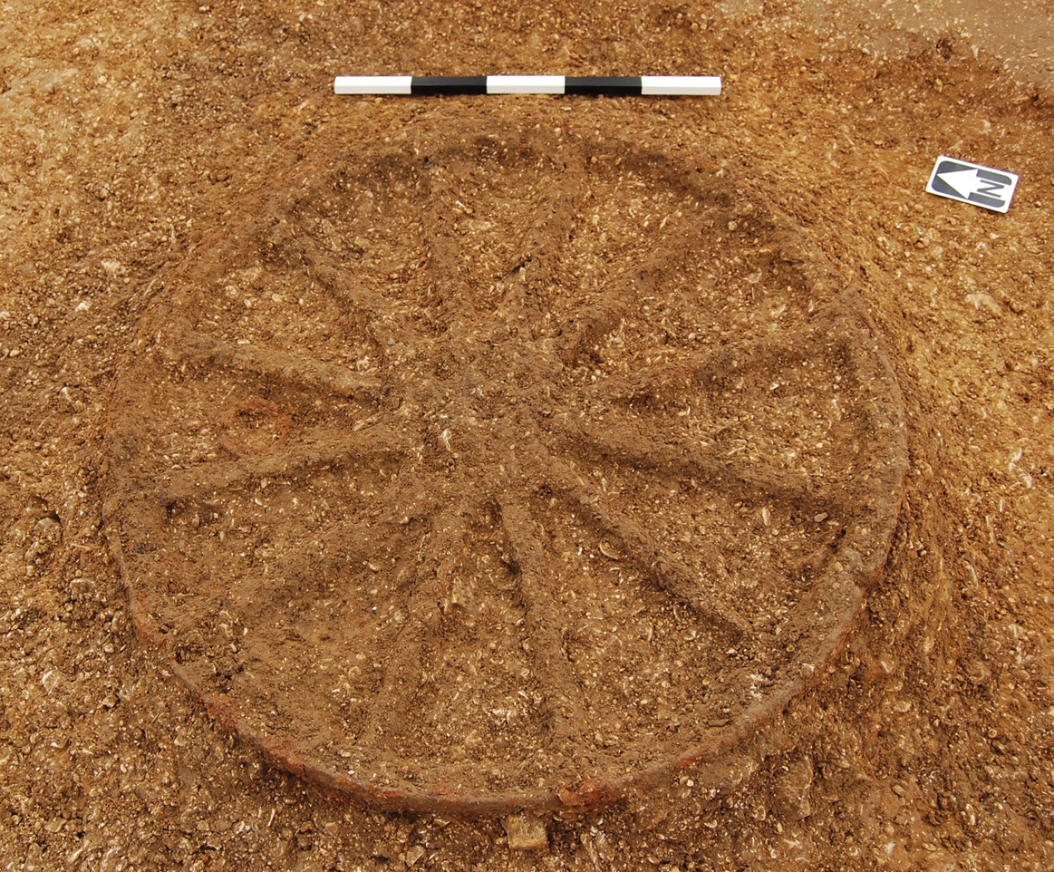 RIGHT Two horse skeletons, the remains of a human, and one chariot wheel from Burnby Lane Barrow 85; ploughing had removed the other wheel and half of the human skeleton. Below The remaining chariot wheel from Burnby Lane Barrow 85: the wooden spokes and rim had rotted but could be picked out through careful excavation of the subtle colour differences in the fill of the grave.