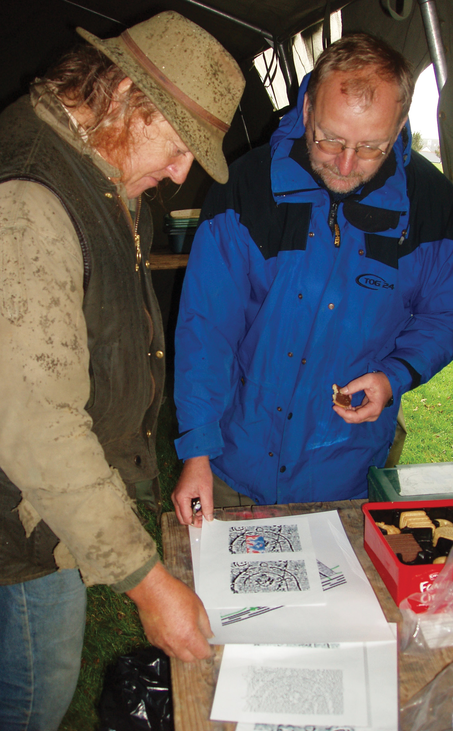 left John Gater, archaeological geophysicist (centre), discusses survey results with Tony Robinson and Mick Aston. This is a key moment of every Time Team episode: where will the trenches be located, and why? below John Gater discusses geophysics survey results with Phil Harding, fortified by the ever-present biscuit tray.