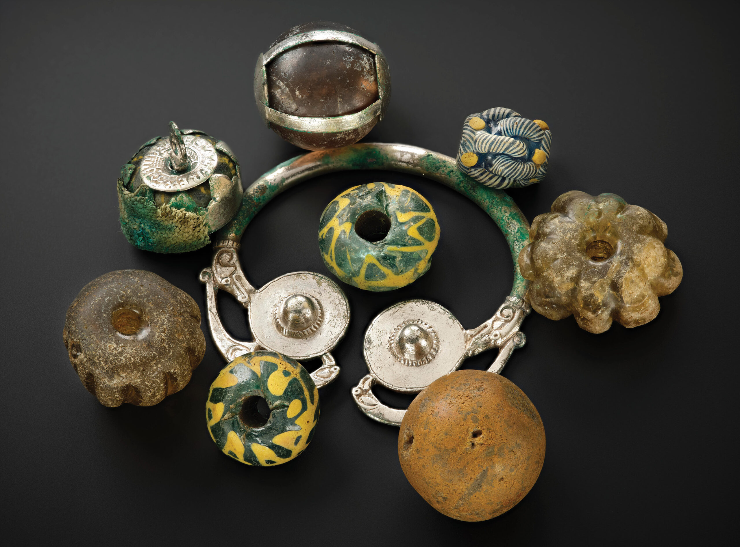 above Beads, curios, and heirloom objects were found together as a group resting on a silver brooch-hoop at the top of the lidded vessel in the Galloway Hoard.
