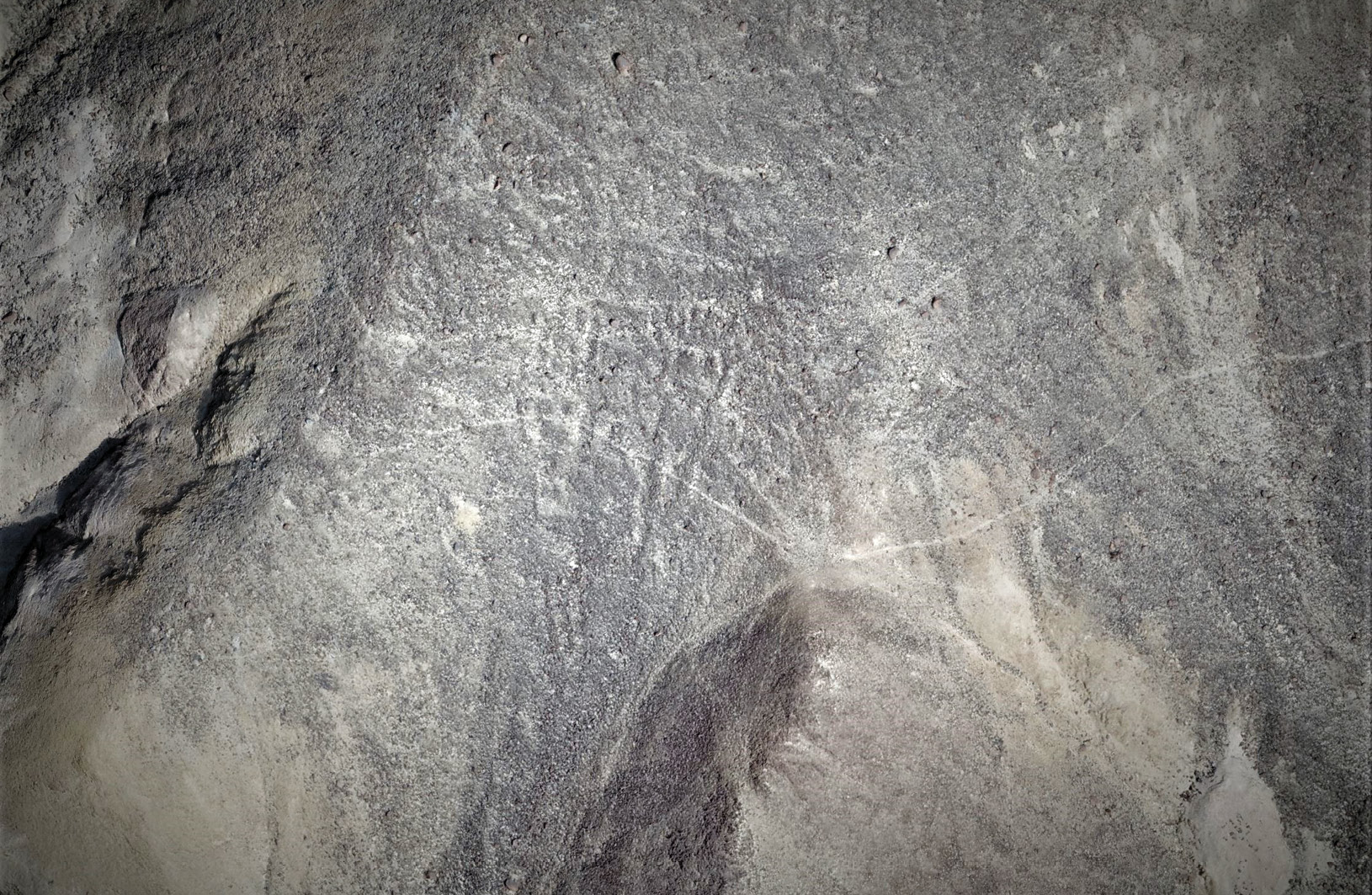 above Newly discovered and faint traces of Palpa figures with headdresses at Yunama, Palpa. Alongside the two visible figures, there are traces of others that are no longer clearly distinct.