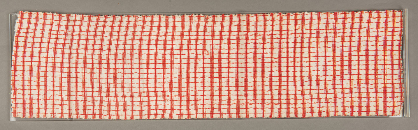 ABOVE This long piece of fabric is a weft-faced plain weave textile in cotton, and red wool with a supplementary red wool warp. These characteristics might hint at origins in the Ewe-speaking region in Ghana and Togo.