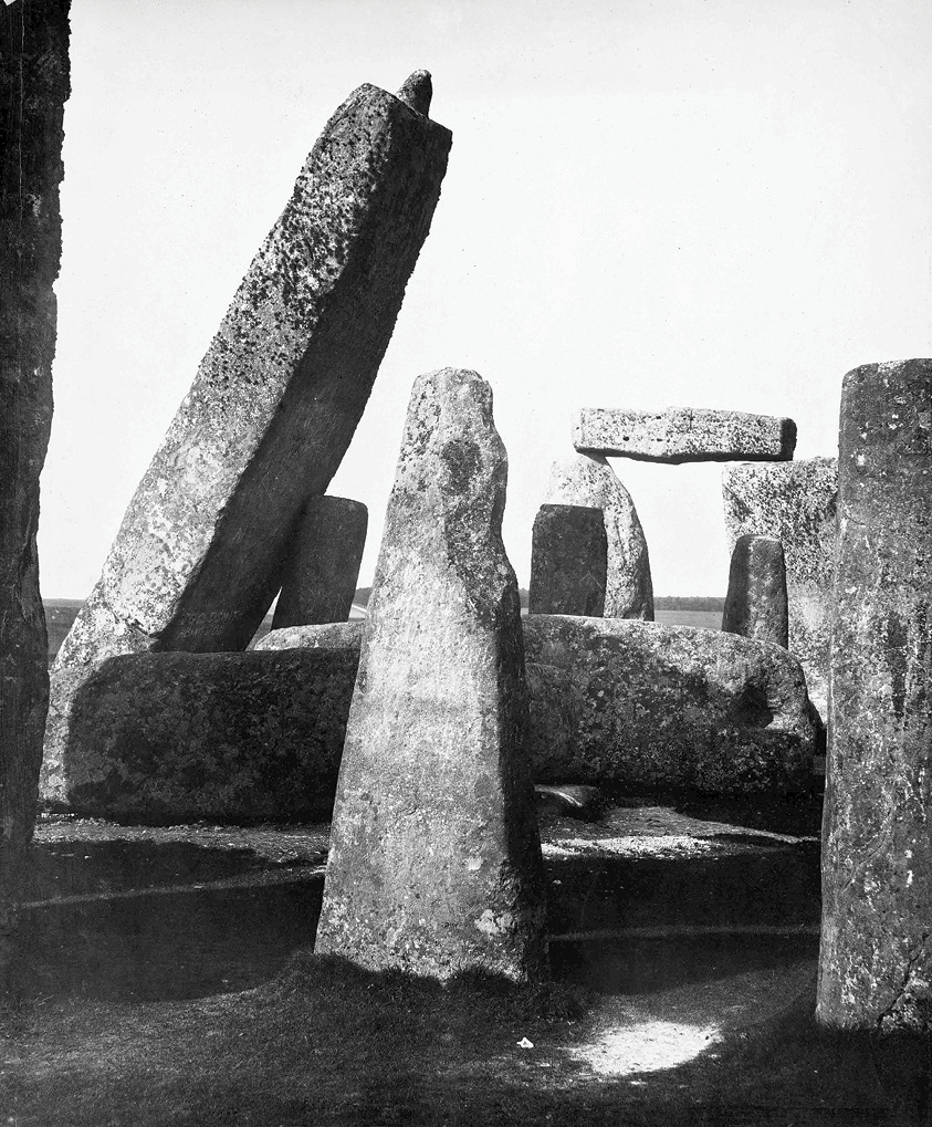 left The Great Trilithon and stone 56, photographed in 1881 by J J Cole. This leaning stone is a central element in the Romantic views of Stonehenge painted by Turner and Constable, and known through many reproductions; despite its alarming angle, there was no contemporary evidence that it was unstable. below The same group of stones, from the opposite direction, shot in the early 1890s with a group of German visitors leaning on stone 56. Improvements in road and rail transport made Stonehenge more accessible in the last decade of the 19th century.