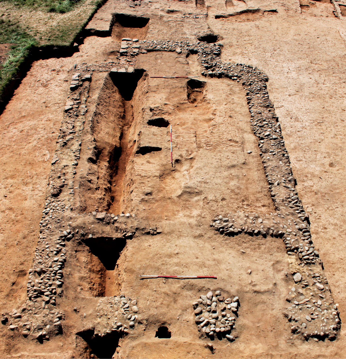 left The remains of the Classical temple excavated outside Maryport Roman fort, as well as the earlier ditch over which it was built. The two columns in antis of the façade can be seen in the foreground. right The pit in which the ‘new’ altar was found. The square post-pipe has been half sectioned on the diagonal, and part of the stone post-packing has been removed, revealing the top of the altar. Its discovery was key to understanding that the altars had not been buried for ritual reasons, but had been recycled as packing material for a monumental building.