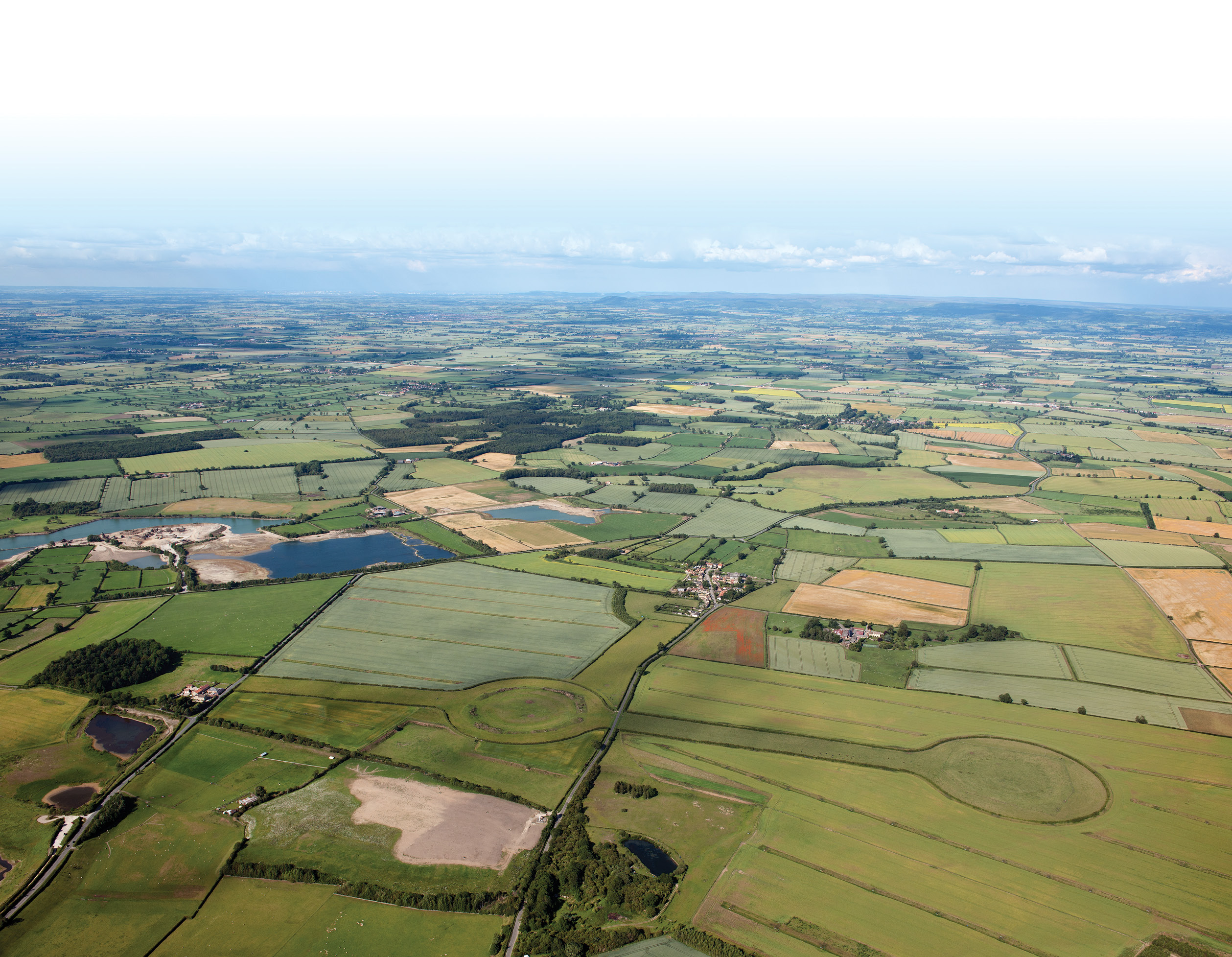 above Thornborough village lies in the centre of the photograph, at the eastern end of the cursus; the road from Thornborough that passes the central henge runs south of, and parallel to, the cursus, whose western terminal lies towards the bottom edge of the photograph.