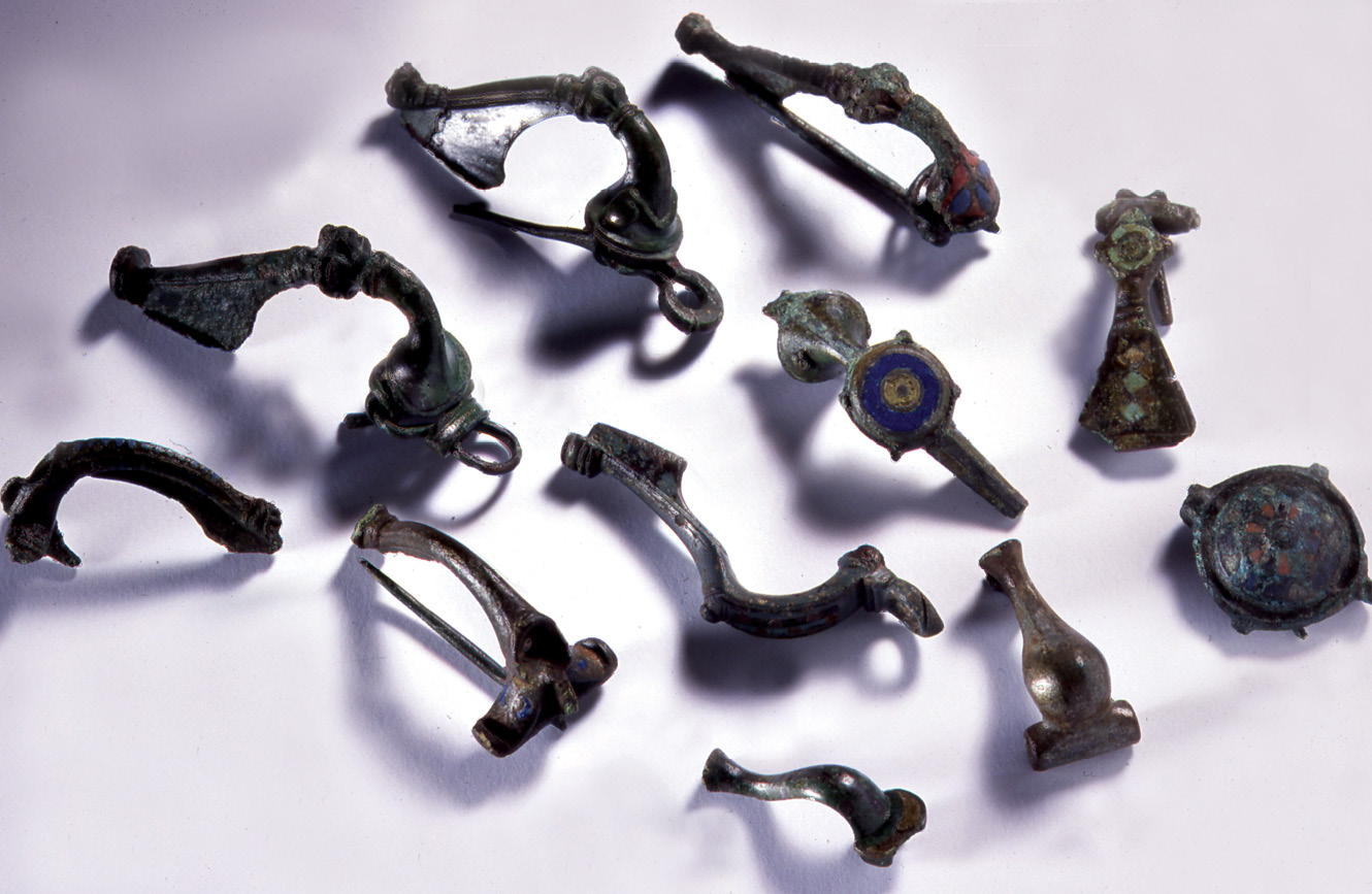 ABOVE A selection of Roman brooches from the hillfort of Traprain Law. TOP RIGHT An intact glass cup from an Iron Age burial at Airlie, Angus. Glass vessels were unknown in the Iron Age, and would have been highly prized imports.