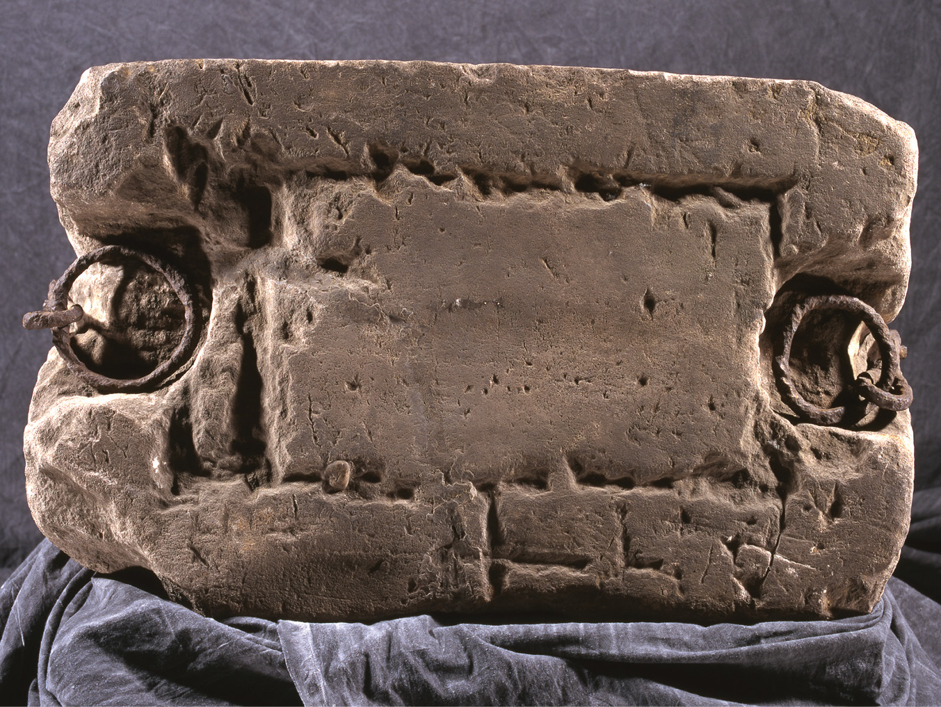 ABOVE The upper face of the Stone of Scone, showing the 16th-century partially cut outline for inserting a brass plate, and the crudely hacked housings enabling the iron rings to lie flat under the newly installed wooden seat.