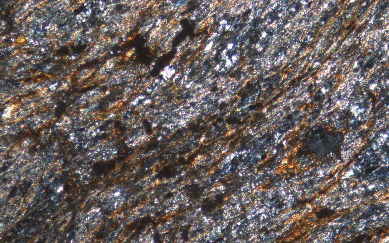 below This photomicrograph shows Volcanic Group A debitage sample SAV08 (015) 1083 from the Stonehenge Avenue, taken in crossed polarised light. It is composed of very fine-grained muscovite interlaminated with quartz and chlorite, as well as minor amounts of titanite and altered ilmenite.