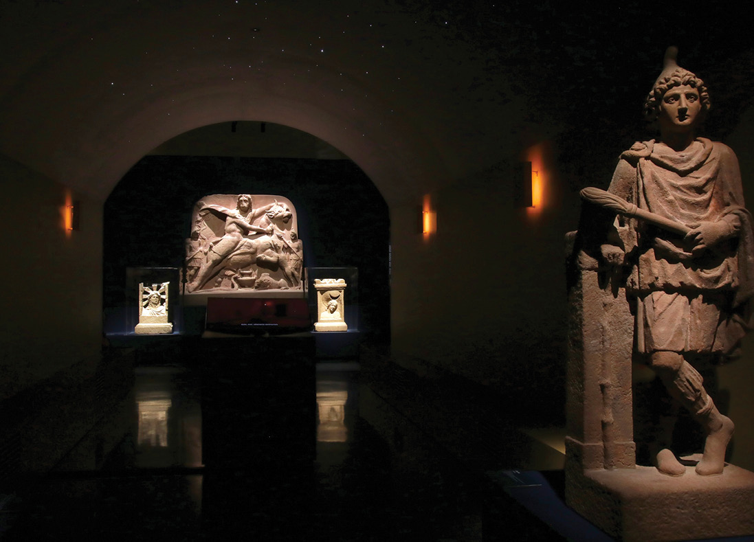 below The entrance to the mithraeum is guarded by the temple’s guardians, Cautes, seen here, holding up a burning torch, and Cautopates, who can be seen on the right of the image above, with a downturned torch.