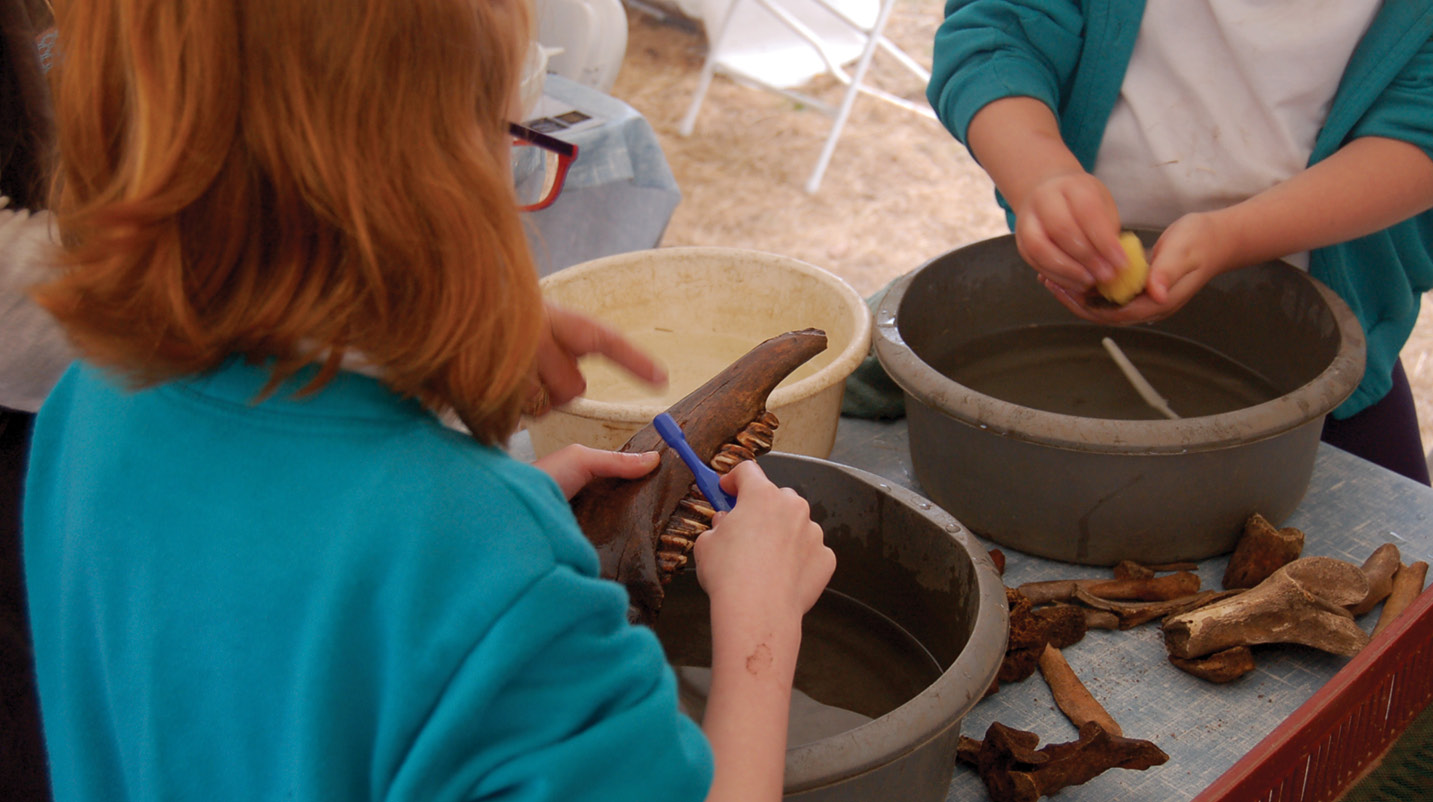 above Local primary school children cleaning animal bones from the site, which were found in such quantities as to suggest major feasts.