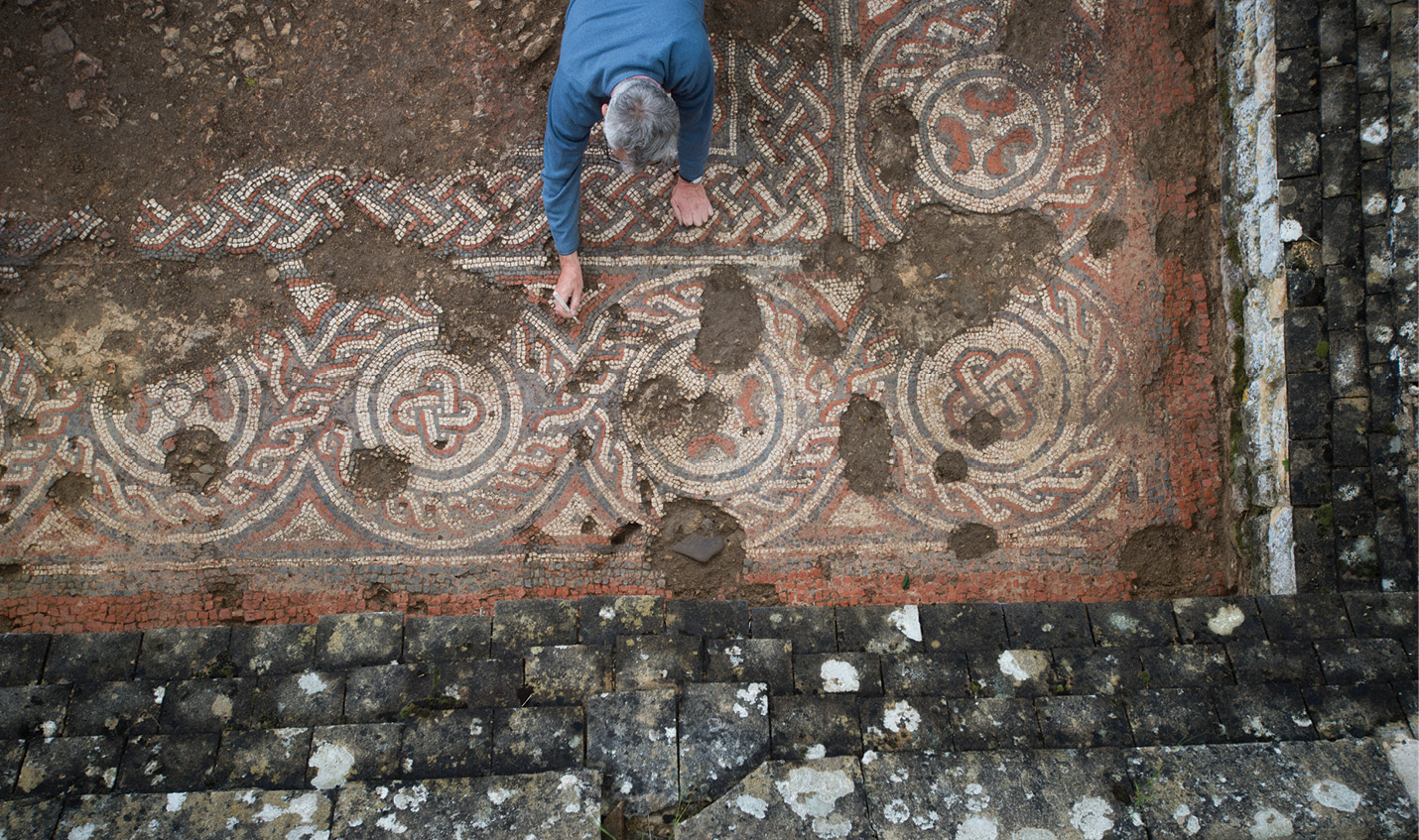 left Excavating the mosaic recently discovered in Room 28, which has been dated to the 5th-6th century. below The 2020 LiDAR survey showing the villa in its combe from the east, with Bronze Age barrows to the north and a possible Iron Age enclosure to the south. In the background is the disused railway.