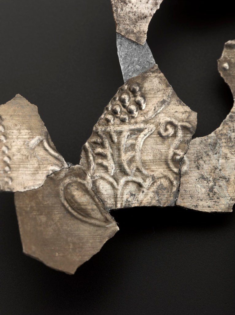 Adorned with the image of a vase heaped with grapes, this fragment probably came from an ornate drinking vessel.