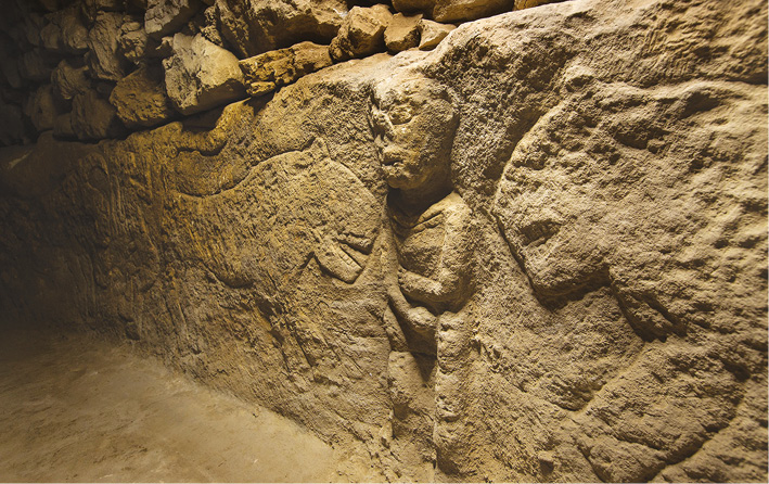 left Detail of a male figure in high-relief, flanked by two leopards, on a bench in a Neolithic building in Sayburç, Turkey. Above Five figures are carved on to the bench, possibly forming two related scenes.