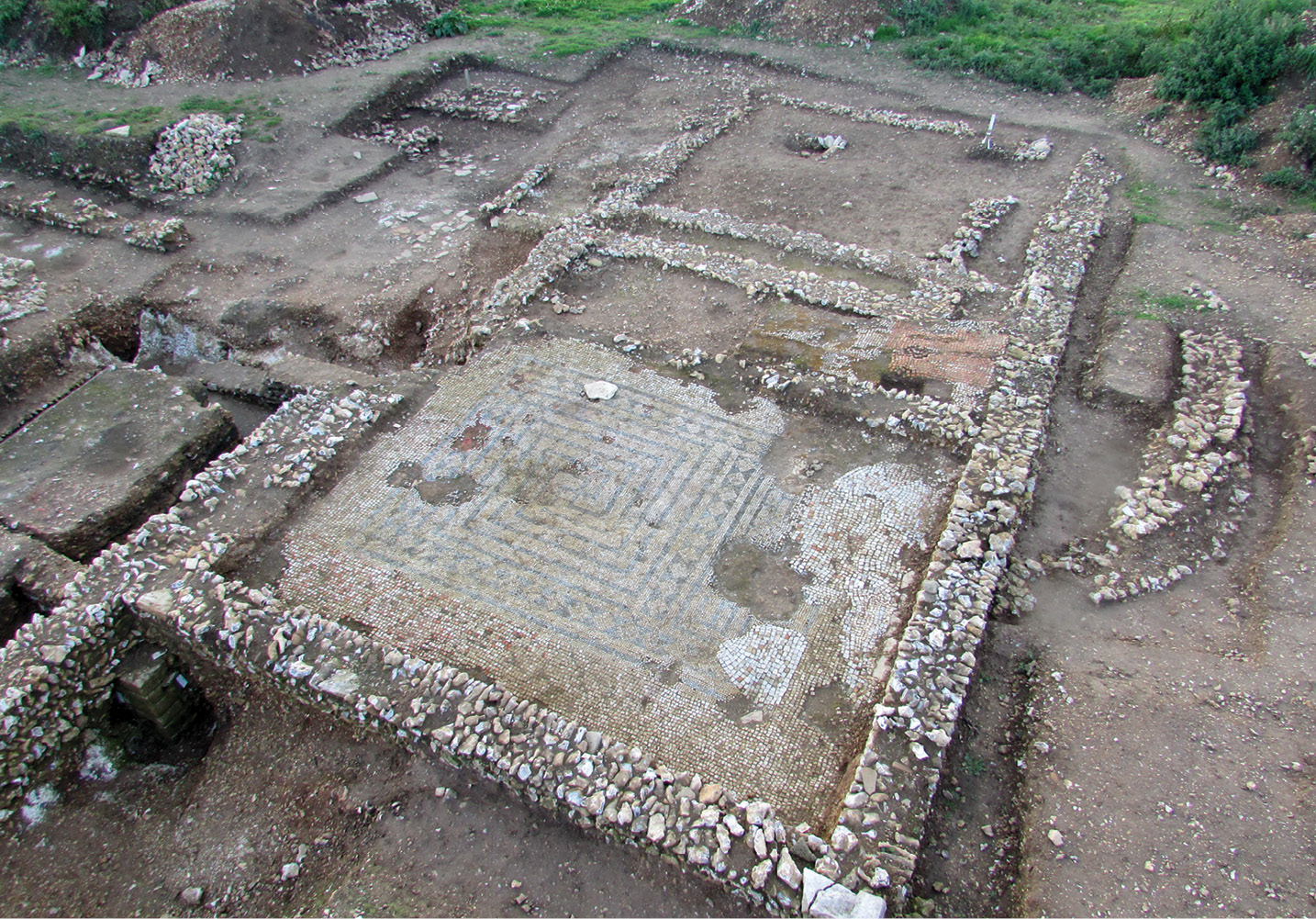 above Rooms N1 (with mosaic), N2, and N5 in the western extension of the north range, dating from phase 4 (after AD 300), with the remains of the phase 2 apse (AD 120-200) on the right. left The west range, probably constructed in the late 2nd century as a single-roomed building with a chalk floor, entered from the courtyard. It was extended and divided into four rooms in AD 250-300, when it housed up to five ovens associated with iron-working, but also capable of being used for cooking.