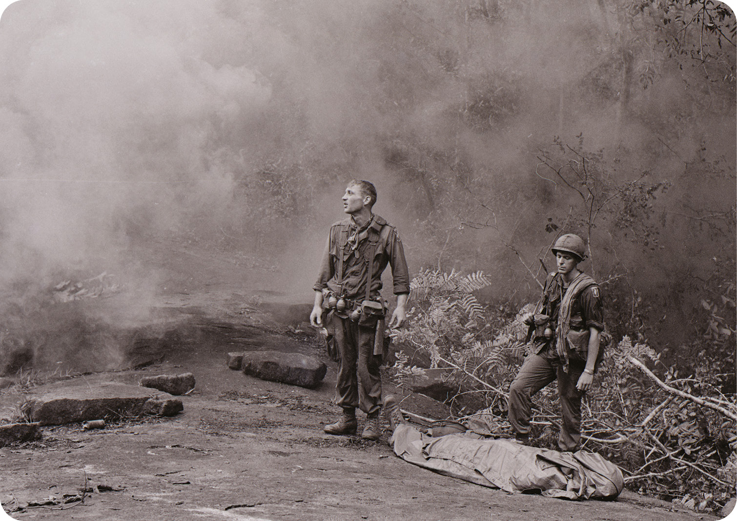 Left US soldiers stand shocked and downcast, alongside the corpse of a fellow serviceman.