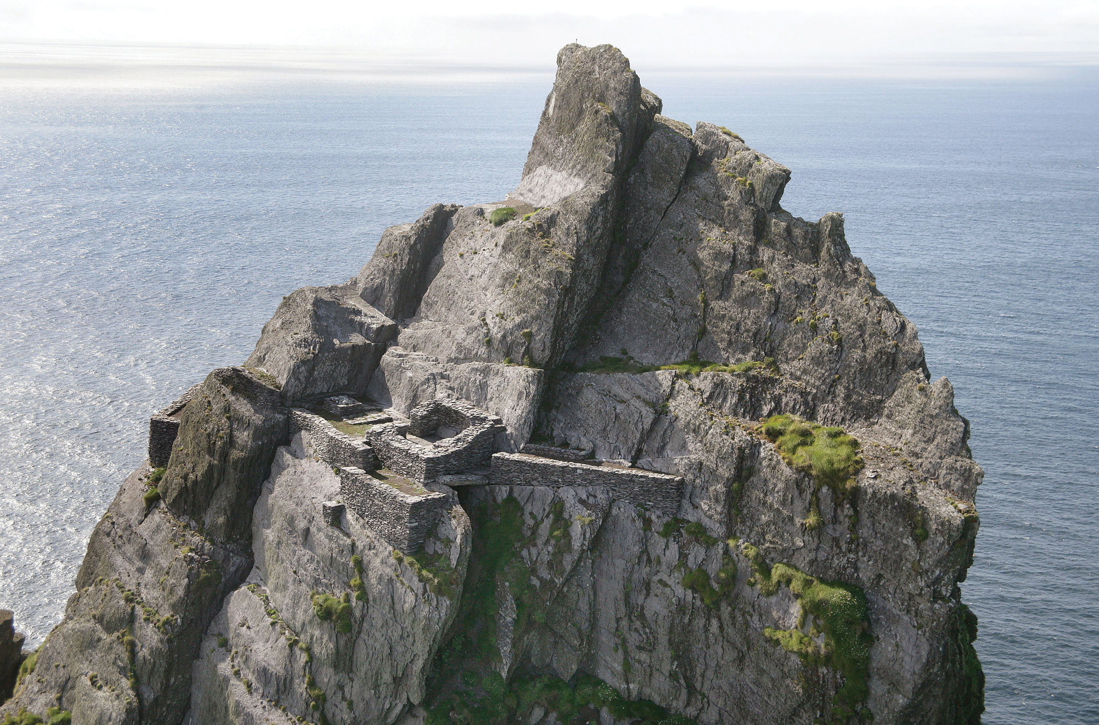 above An aerial view of the head-spinning location of the hermitage, daringly constructed below the south peak. left The main oratory terrace at the hermitage from which you can just see down on to the terraces of the main monastery to the right of the picture. Beyond this is Skellig Michael’s smaller counterpart, Skellig Beag, then the Iveragh mainland. The tiny oratory has a partly preserved altar and a small quartz-covered leacht, which probably supported a standing cross. Water was captured by rock-cut channels that fed into the small stone cistern to the left of the oratory entrance.