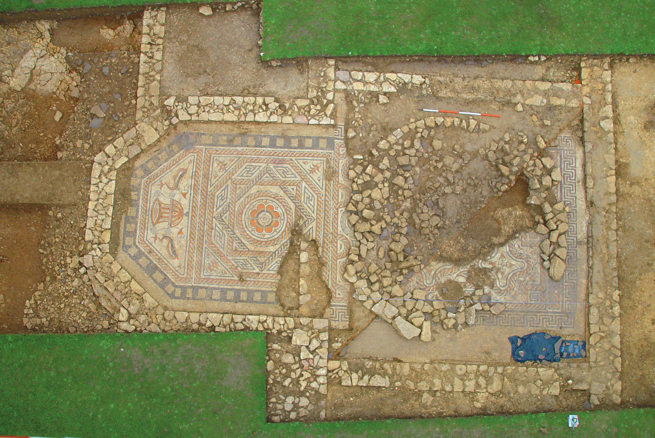 above Building 1 at St Laurence School villa, Bradford-on-Avon, with its mosaic and a circular stone platform that has been interpreted as the base for a baptismal font. below The mosaic in the apse of Building 1 at Bradford-on-Avon, depicting two dolphins either side of a cantharus (a ceremonial wine jar).